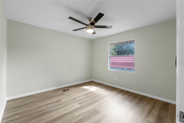 spare room with light wood-style floors, visible vents, ceiling fan, and baseboards