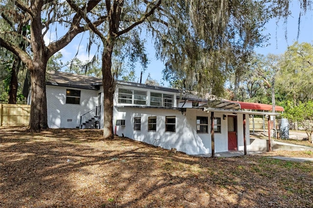 rear view of property featuring brick siding, crawl space, and fence