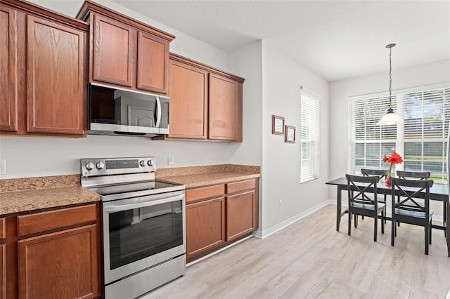 kitchen with appliances with stainless steel finishes, light hardwood / wood-style flooring, and decorative light fixtures