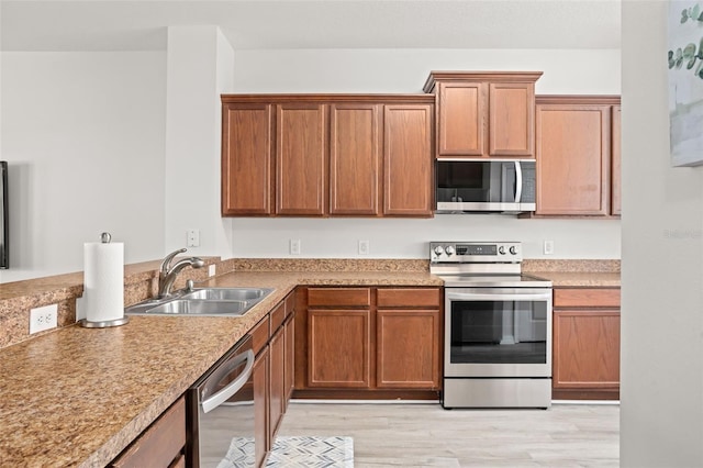 kitchen with sink, stainless steel appliances, and light hardwood / wood-style floors