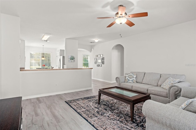 living room featuring light wood-type flooring, ceiling fan, and a healthy amount of sunlight