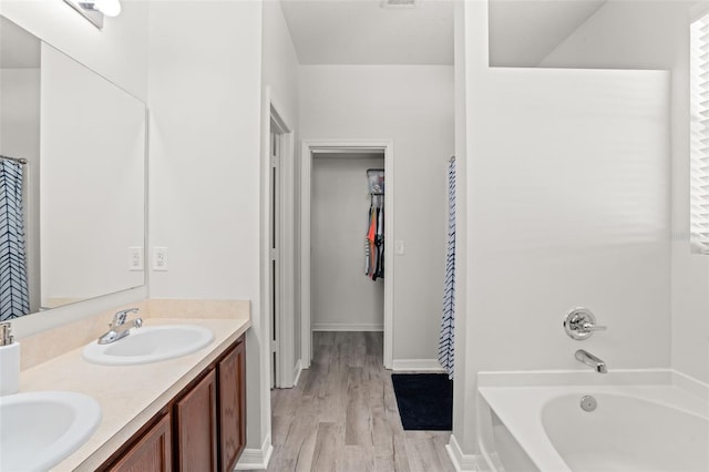 bathroom with a tub to relax in, vanity, and hardwood / wood-style floors