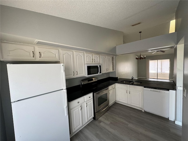 kitchen featuring white appliances, a sink, visible vents, white cabinetry, and dark countertops