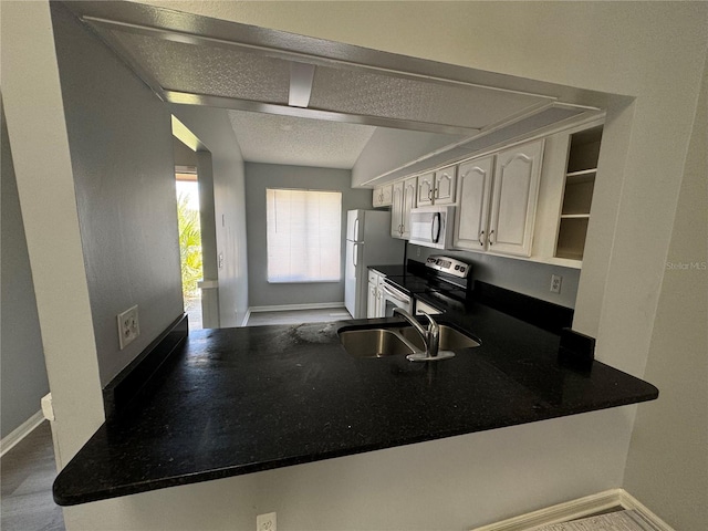 kitchen featuring open shelves, appliances with stainless steel finishes, dark countertops, and a peninsula