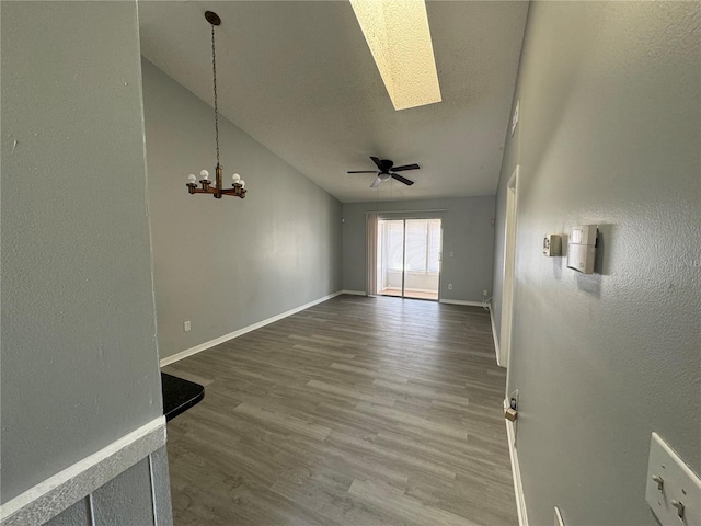 interior space featuring a textured ceiling, baseboards, wood finished floors, and ceiling fan with notable chandelier