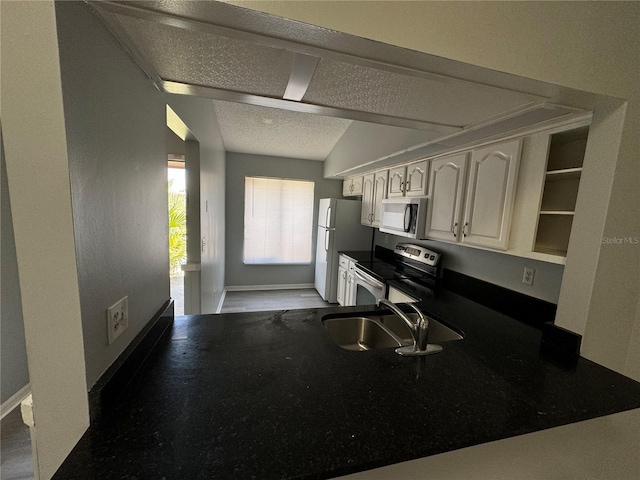 kitchen with dark countertops, stainless steel appliances, a textured ceiling, open shelves, and a sink