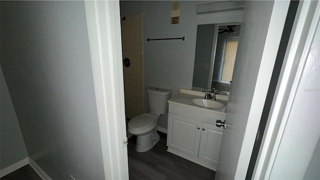 full bath with tiled shower, vanity, toilet, and wood finished floors