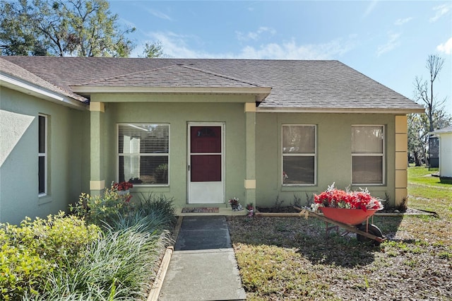 property entrance with roof with shingles and stucco siding