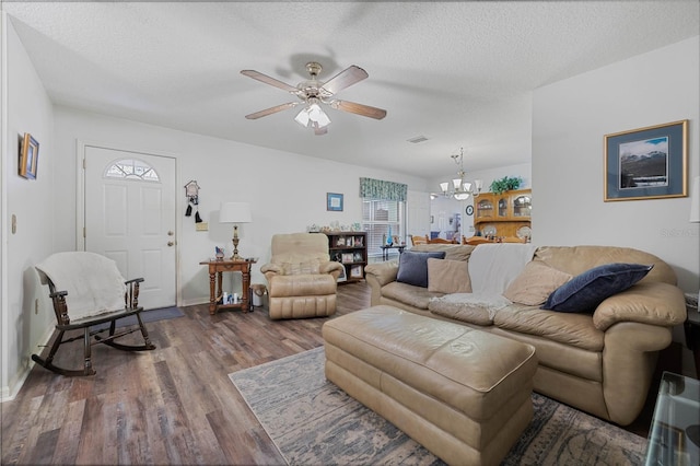 living room featuring a textured ceiling, ceiling fan with notable chandelier, wood finished floors, visible vents, and baseboards