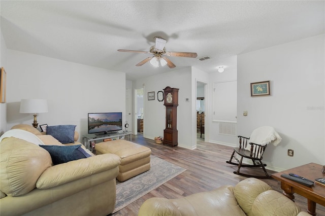 living room with visible vents, light wood-style flooring, a ceiling fan, a textured ceiling, and baseboards