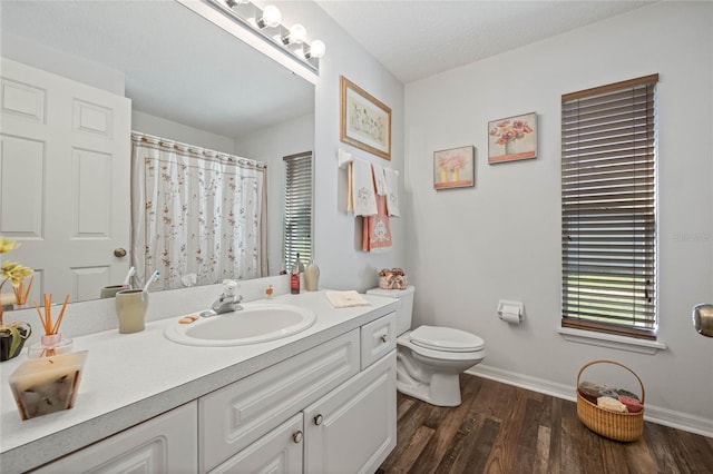 full bath featuring a textured ceiling, toilet, wood finished floors, vanity, and baseboards