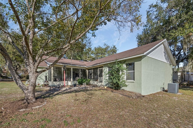 view of front of property featuring a sunroom, a front lawn, cooling unit, and stucco siding