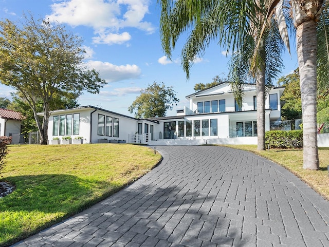 view of front facade featuring a front lawn, decorative driveway, and stucco siding