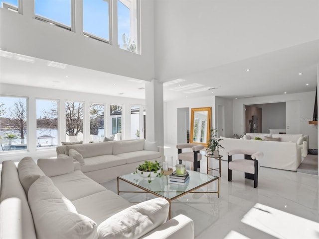 living room with marble finish floor, a high ceiling, and recessed lighting