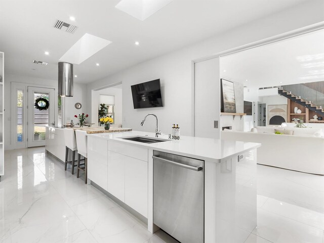 kitchen featuring dishwasher, light countertops, a spacious island, and white cabinetry