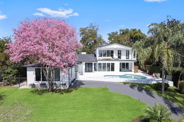 back of house with a fenced in pool, a yard, a chimney, fence, and a balcony