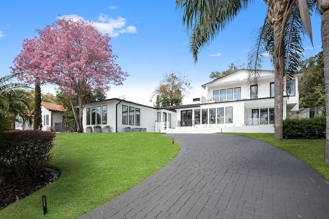 view of front of home featuring a front yard, decorative driveway, and stucco siding