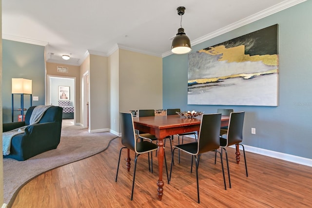 dining space featuring ornamental molding, wood finished floors, and baseboards