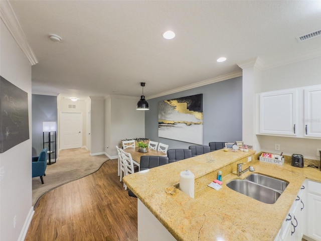 8000 Tuscany Way Unit 4405, Davenport, FL 33896 - kitchen featuring a peninsula, white cabinets, wood finished floors, light stone countertops, and ornamental molding