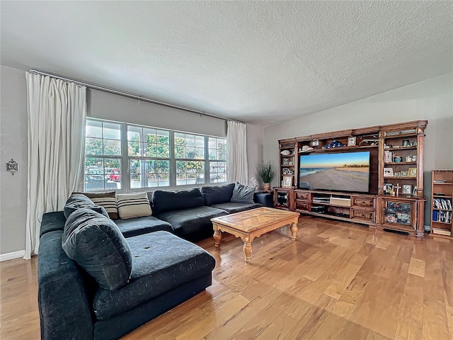 living room with a textured ceiling, vaulted ceiling, and light hardwood / wood-style flooring