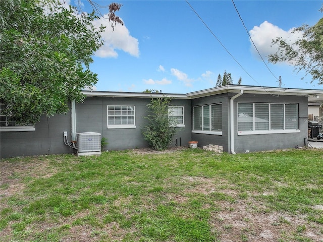 rear view of house featuring a lawn and central air condition unit