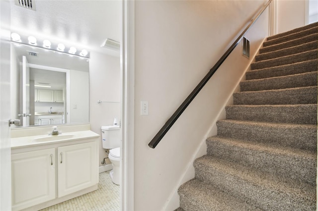 stairs featuring sink and tile patterned flooring