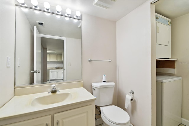 bathroom with toilet, vanity, and stacked washer and dryer