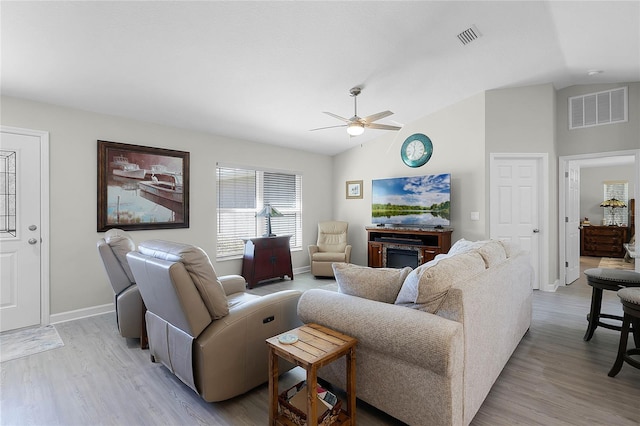 living room featuring vaulted ceiling, visible vents, and light wood-style floors