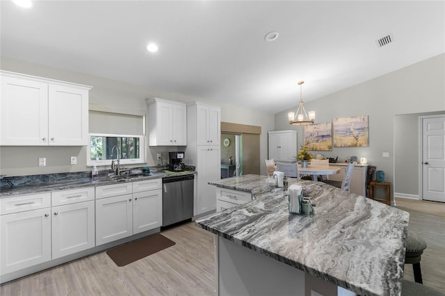 kitchen featuring light stone counters, a sink, a kitchen island, white cabinetry, and stainless steel dishwasher