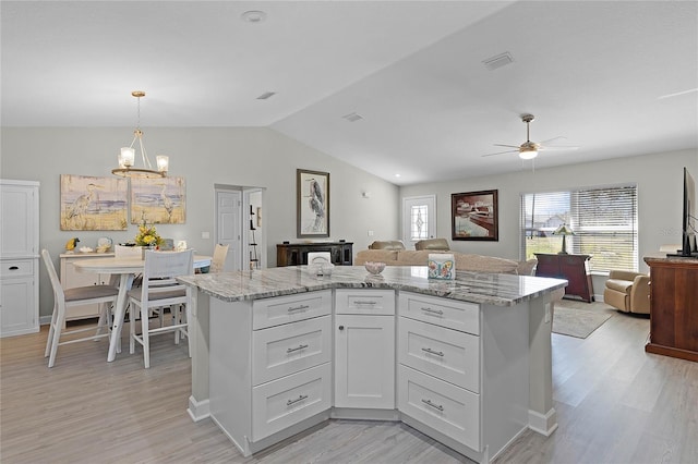 kitchen featuring white cabinets, light stone counters, and open floor plan