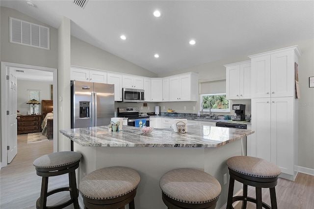 kitchen featuring visible vents, appliances with stainless steel finishes, white cabinetry, and a center island