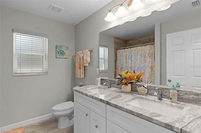 full bathroom with toilet, a sink, and visible vents