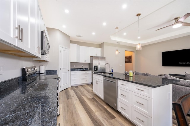 kitchen with appliances with stainless steel finishes, white cabinets, and hanging light fixtures