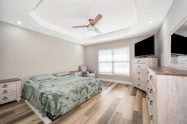 bedroom featuring hardwood / wood-style flooring, ceiling fan, and a raised ceiling