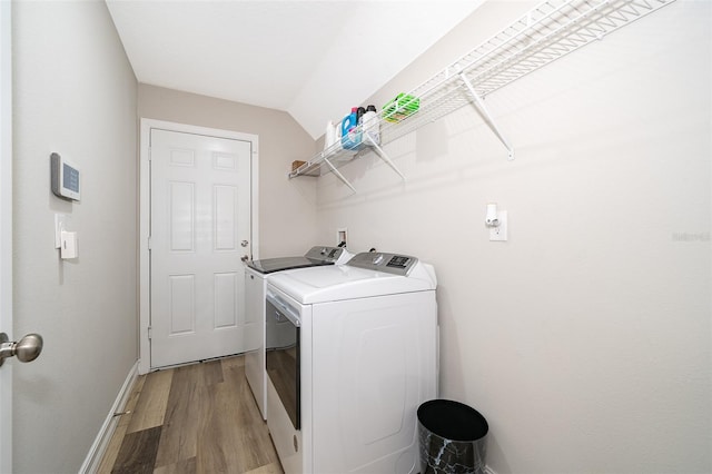 clothes washing area with washer and dryer and light wood-type flooring