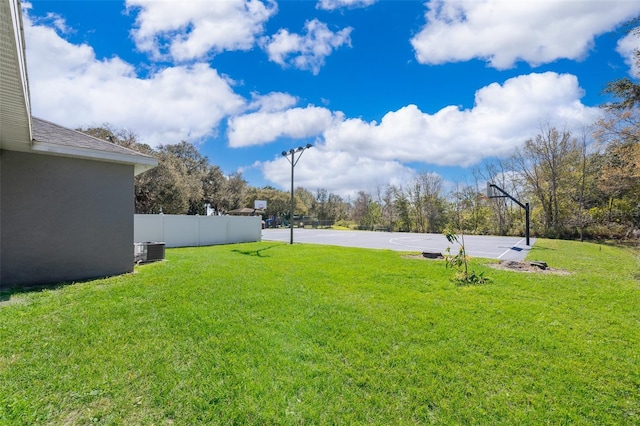 view of yard with central air condition unit and basketball hoop