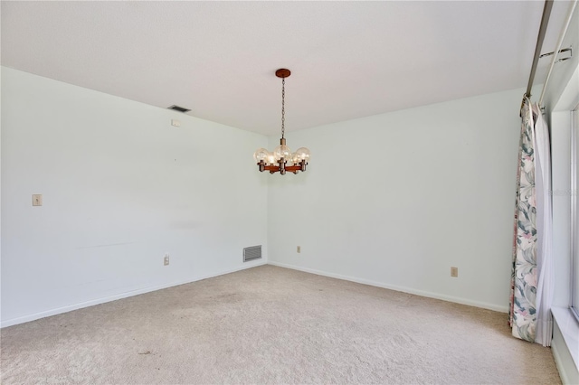 spare room featuring carpet flooring and an inviting chandelier