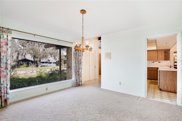 unfurnished dining area featuring a notable chandelier, sink, and light colored carpet