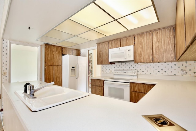 kitchen featuring white appliances, sink, and kitchen peninsula