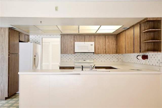 kitchen with white appliances, sink, and kitchen peninsula