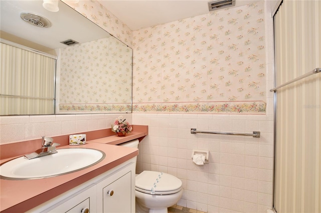 bathroom featuring tile walls, vanity, and toilet