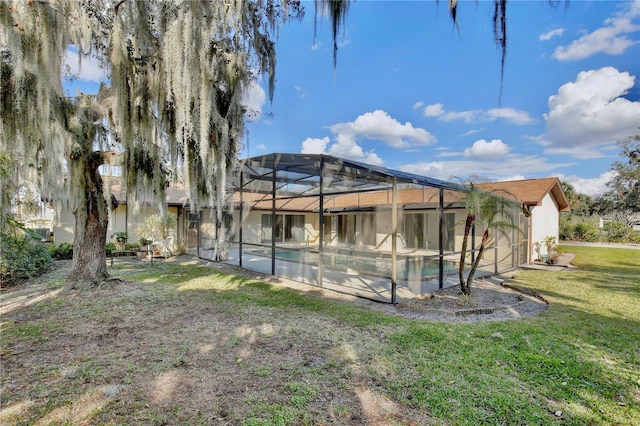 back of property featuring glass enclosure and a lawn