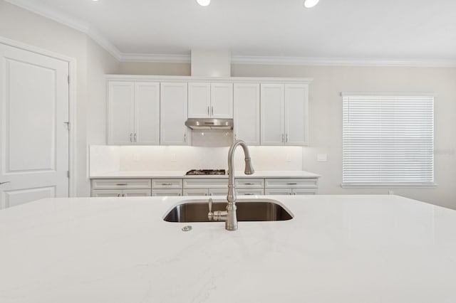 kitchen featuring a sink, gas stovetop, white cabinetry, and under cabinet range hood