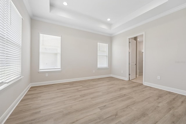 spare room featuring a tray ceiling, light wood-type flooring, plenty of natural light, and recessed lighting