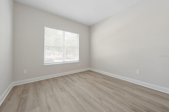 spare room with baseboards and light wood-style floors