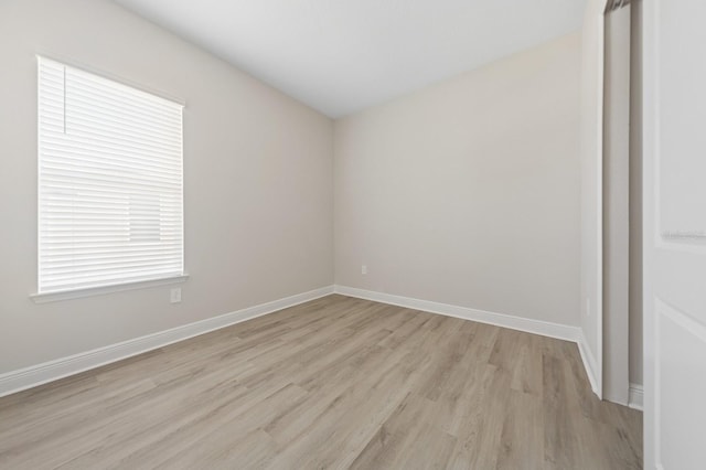 spare room with baseboards and light wood-style floors