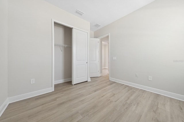 unfurnished bedroom with baseboards, light wood-style floors, a closet, and visible vents
