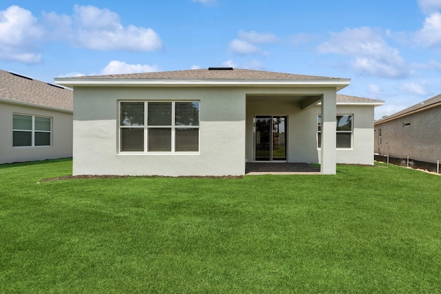 back of property with a yard and stucco siding
