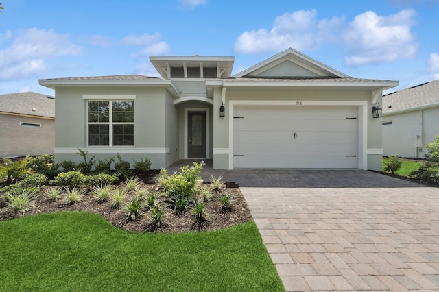 view of front of home featuring a front yard, stucco siding, decorative driveway, and a garage