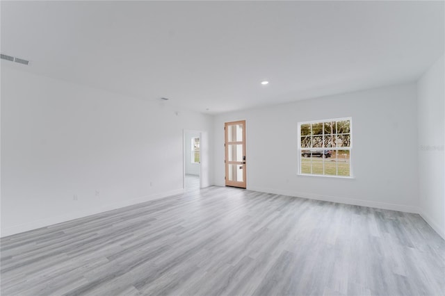 unfurnished room with light wood finished floors, visible vents, and baseboards